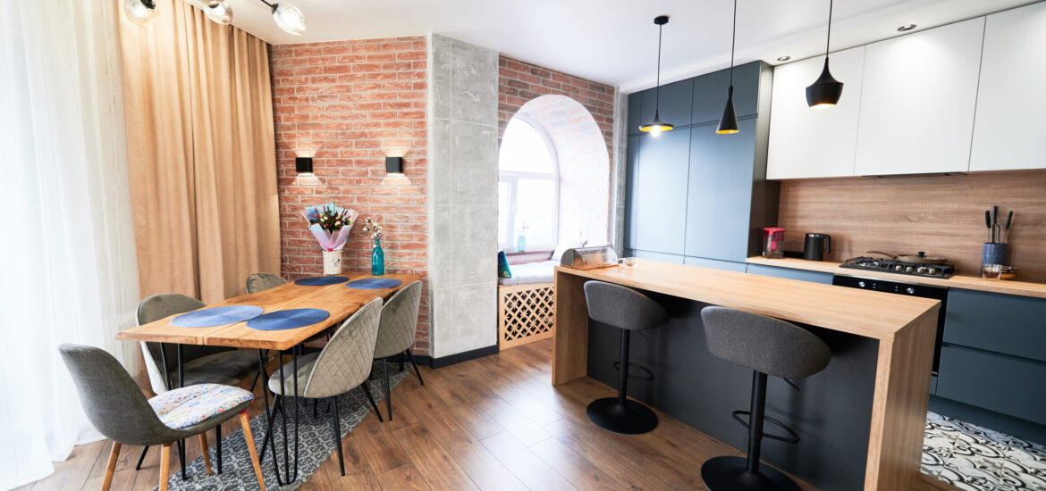 Living room and kitchen studio in dark blue color with modern furniture table, chair and stylish lamps. Concept of stylish modern interior kitchen with bar table.